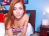 A cute looking red haired teen gets naked on cam